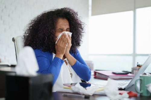 Woman sat at desk with hay fever doing exams